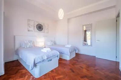 a white bedroom with two beds and a mirror at Apartamento Jasmineiro - By WeHost in Funchal