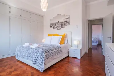 a white bedroom with a large bed and a wooden floor at Apartamento Jasmineiro - By WeHost in Funchal