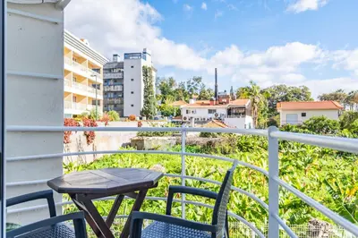 a table and chairs on a balcony with a view of a city at Navio Azul Apartment in Funchal