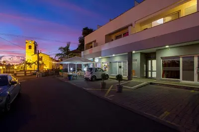 a parking lot in front of a building with a clock tower at Apartamento do Avô Tomás in Madalena do Mar