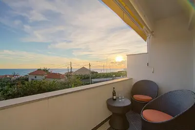 a balcony with two chairs and a table and a view of the ocean at Apartamento do Avô Tomás in Madalena do Mar