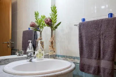 a bathroom with a sink and a vase with flowers at Apartamento do Avô Tomás in Madalena do Mar