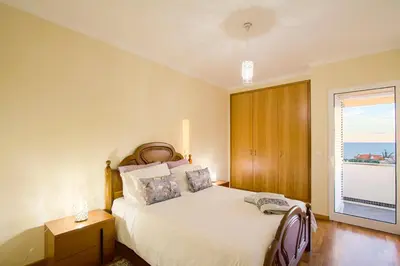 a bedroom with a bed and a large window at Apartamento do Avô Tomás in Madalena do Mar
