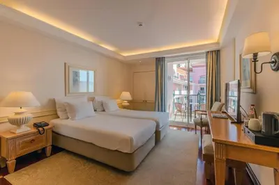 a bedroom with a bed and a desk and a window at Pestana Royal All Inclusive Ocean & Spa Resort in Funchal