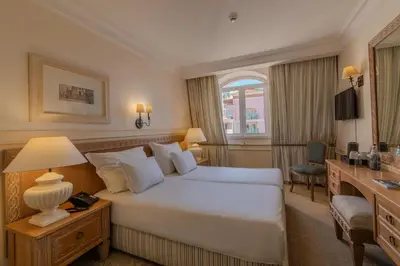 a hotel room with a white bed and a desk and a desk at Pestana Royal All Inclusive Ocean & Spa Resort in Funchal