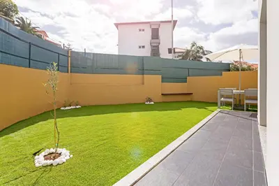 a backyard with a yellow fence and green grass at Pena I by An Island Apart in Funchal