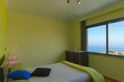 a bedroom with a bed and a large window at Casa do Serrado in Ponta do Sol