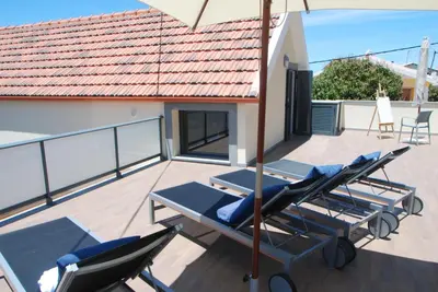 a row of lounge chairs and an umbrella on a balcony at Serenity in Jardim do Mar