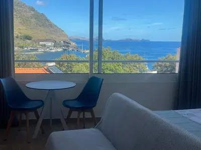 a room with a table and chairs and a large window at Feeling Like Home Machico in Machico