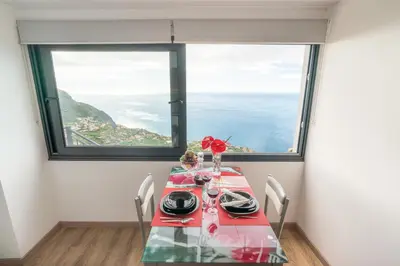 a dining room with a table and a large window at Casa da Tenda in Arco da Calheta