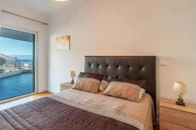 a bedroom with a large bed with a large window at Virtudes Ocean view with pool by Holiday Rental Madeira in Funchal