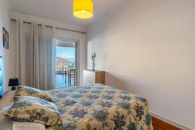 a bedroom with a bed with a pillow and a window at Virtudes Ocean view with pool by Holiday Rental Madeira in Funchal
