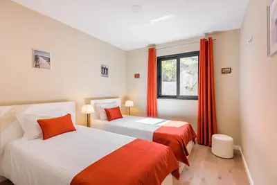 two beds in a room with orange curtains at Funchal SilverWood Apartment - by LovelyStay in Funchal