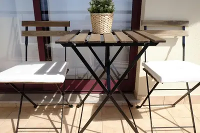 a table with two chairs and a potted plant on it at FLH Garajau Balcony with Pool in Caniço