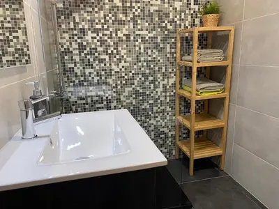 a bathroom with a sink and a shelf with towels at FLH Garajau Balcony with Pool in Caniço