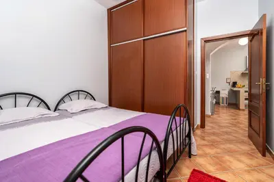 a bedroom with a bed with purple sheets and a closet at Casa das Camélias in Arco da Calheta