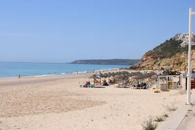 a beach with chairs and umbrellas and people on it at Salema Beach Private Villa in Salema