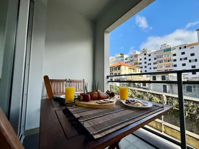 a table with a plate of food on a balcony at Madeira Emotions Apartments in Funchal