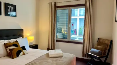 a bedroom with a bed and a window and a chair at Madeira Emotions Apartments in Funchal