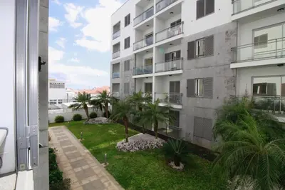 an apartment building with palm trees in the yard at Madeira Emotions Apartments in Funchal