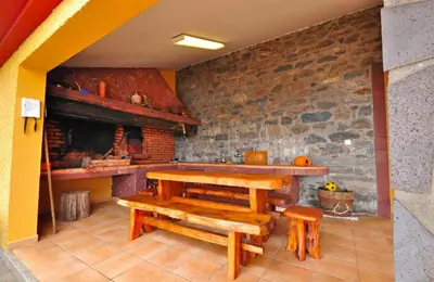 a room with a table and benches and a fireplace at Casa da Rocha in Calheta