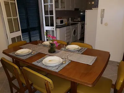 a dining room table with chairs and a wooden table with plates at Apartment with beautiful ocean and city view in Funchal