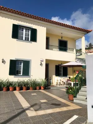 a white house with green shutters and a patio at Apartment with beautiful ocean and city view in Funchal