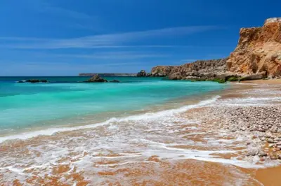 a beach with turquoise water and a rocky coastline at Sagres Sunny Room with private bathroom 300m from the beach in Sagres