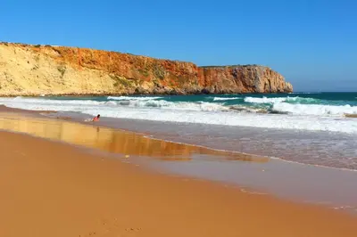 a person standing in the water at the beach at Sagres Sunny Room with private bathroom 300m from the beach in Sagres