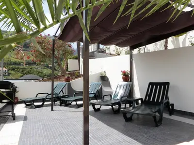 a group of chairs under an umbrella on a patio at Vivenda Linda Vista in Porto da Cruz