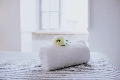 a white pillow with a flower on top of a bed at Paul do Mar Beach House in Paul do Mar