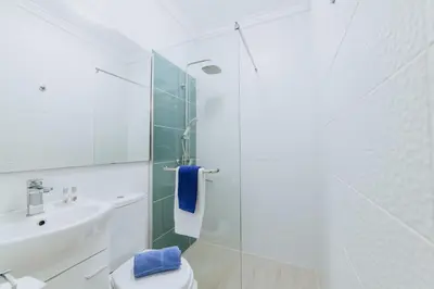 a white bathroom with a sink and a toilet at Paul do Mar Beach House in Paul do Mar