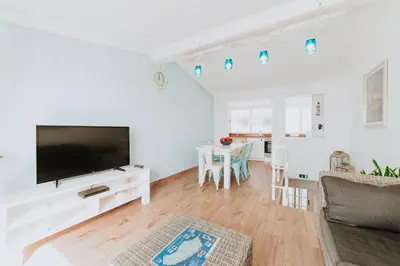 a living room with a flat screen tv and a table at Paul do Mar Beach House in Paul do Mar