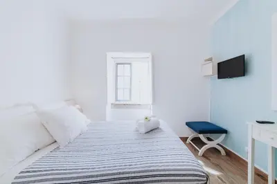 a white bedroom with a bed and a tv at Paul do Mar Beach House in Paul do Mar