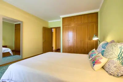 a bedroom with a large bed and a mirror at Quinta Falesia Apartment in Funchal