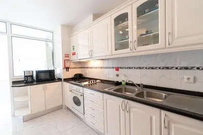 a kitchen with white cabinets and a sink and a window at Apartamento Alberto in Funchal