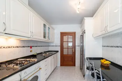 a kitchen with white cabinets and a stove top oven at Apartamento Alberto in Funchal