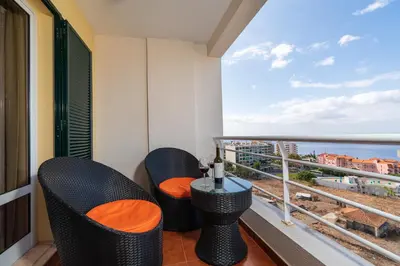 a balcony with chairs and a table and a view of the ocean at Apartamento Alberto in Funchal