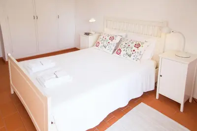 a bedroom with a white bed and a white cabinet at FLH Praia da Luz House with Terrace in Luz