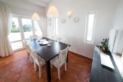 a dining room with a black table and white chairs at FLH Praia da Luz House with Terrace in Luz