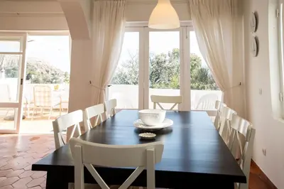 a dining room with a black table and white chairs at FLH Praia da Luz House with Terrace in Luz