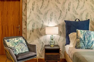 a bedroom with a bed and a chair and a lamp at Queimada Houses in Funchal