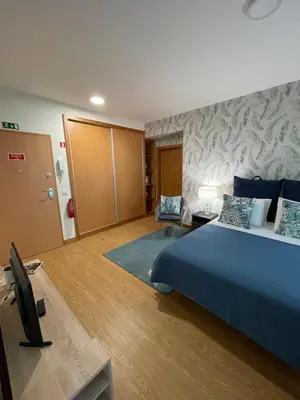 a hotel room with a bed and a television at Queimada Houses in Funchal