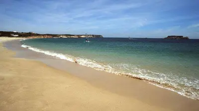 a beach with the ocean and a boat in the water at OCEANUS ROOM With private kitchen, bathroom and terrace 300m from the beach in Sagres