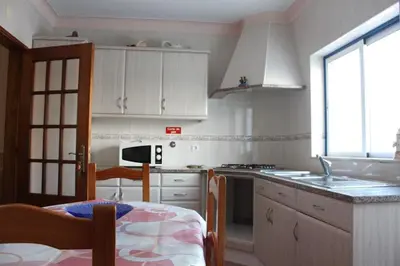 a kitchen with white cabinets and a sink and a table at OCEANUS ROOM With private kitchen, bathroom and terrace 300m from the beach in Sagres