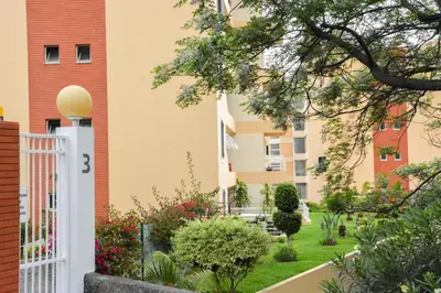 a garden in front of a building with a white fence at Vista Formosa Funchal in Funchal