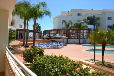 a resort with a pool and palm trees and lounge chairs at Bel appartement au bord de la mer de Porto de Mos in Lagos