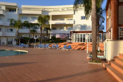 a resort with chairs and a pool and a building at Bel appartement au bord de la mer de Porto de Mos in Lagos
