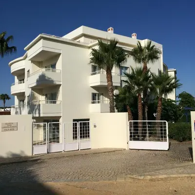 a white building with palm trees in front of it at Bel appartement au bord de la mer de Porto de Mos in Lagos