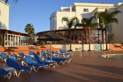 a group of chairs and umbrellas on a patio at Bel appartement au bord de la mer de Porto de Mos in Lagos